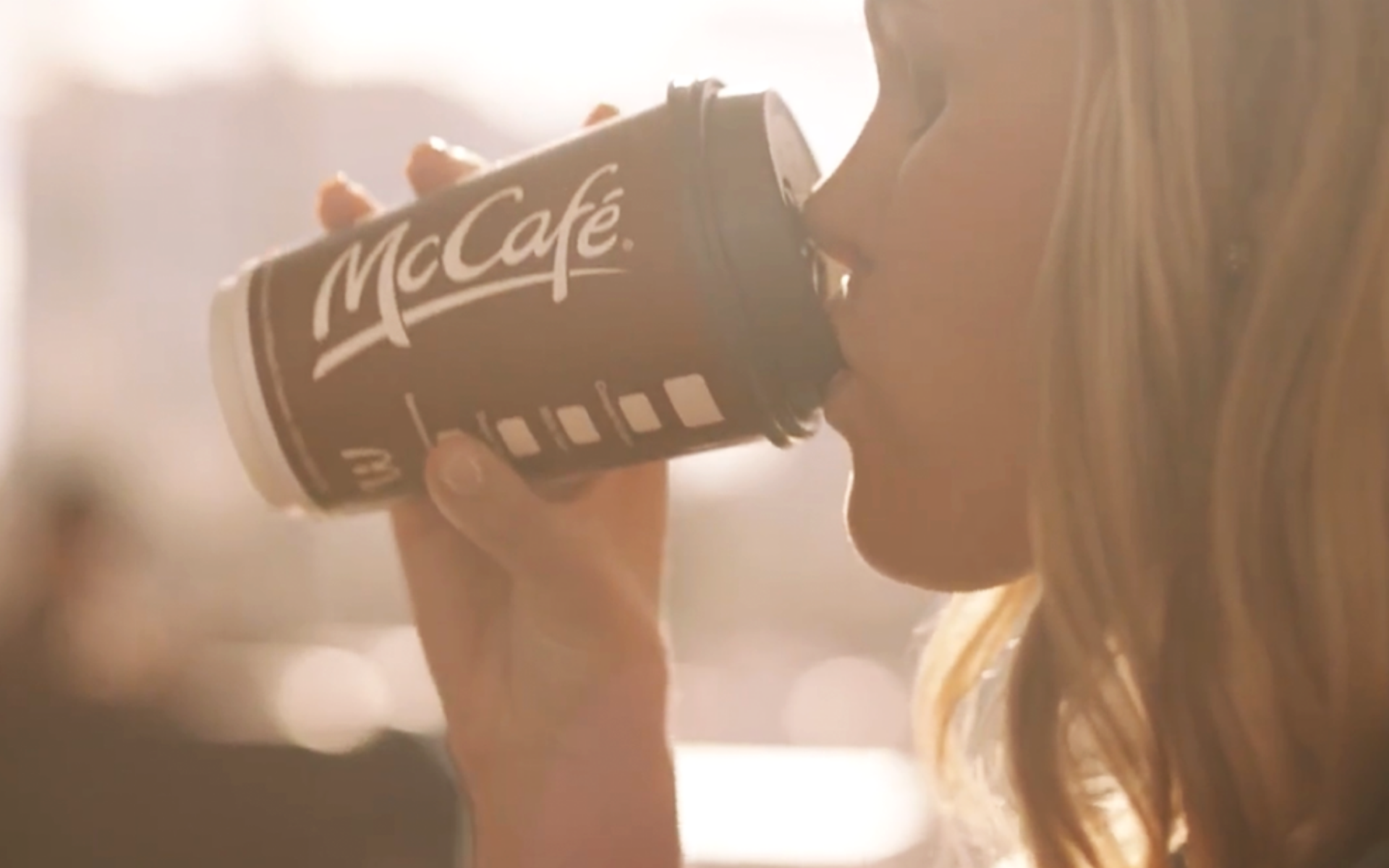 Young woman taking a sip of a McCafe premium roast specialty coffee.